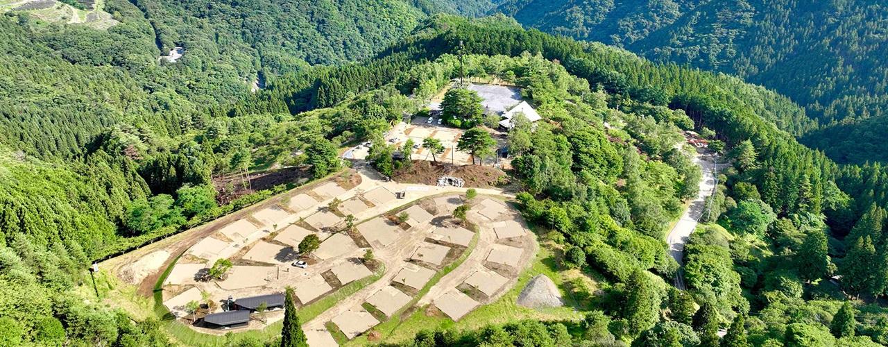 ドローンで上空から撮影した山の緑に囲まれたキャンプ場