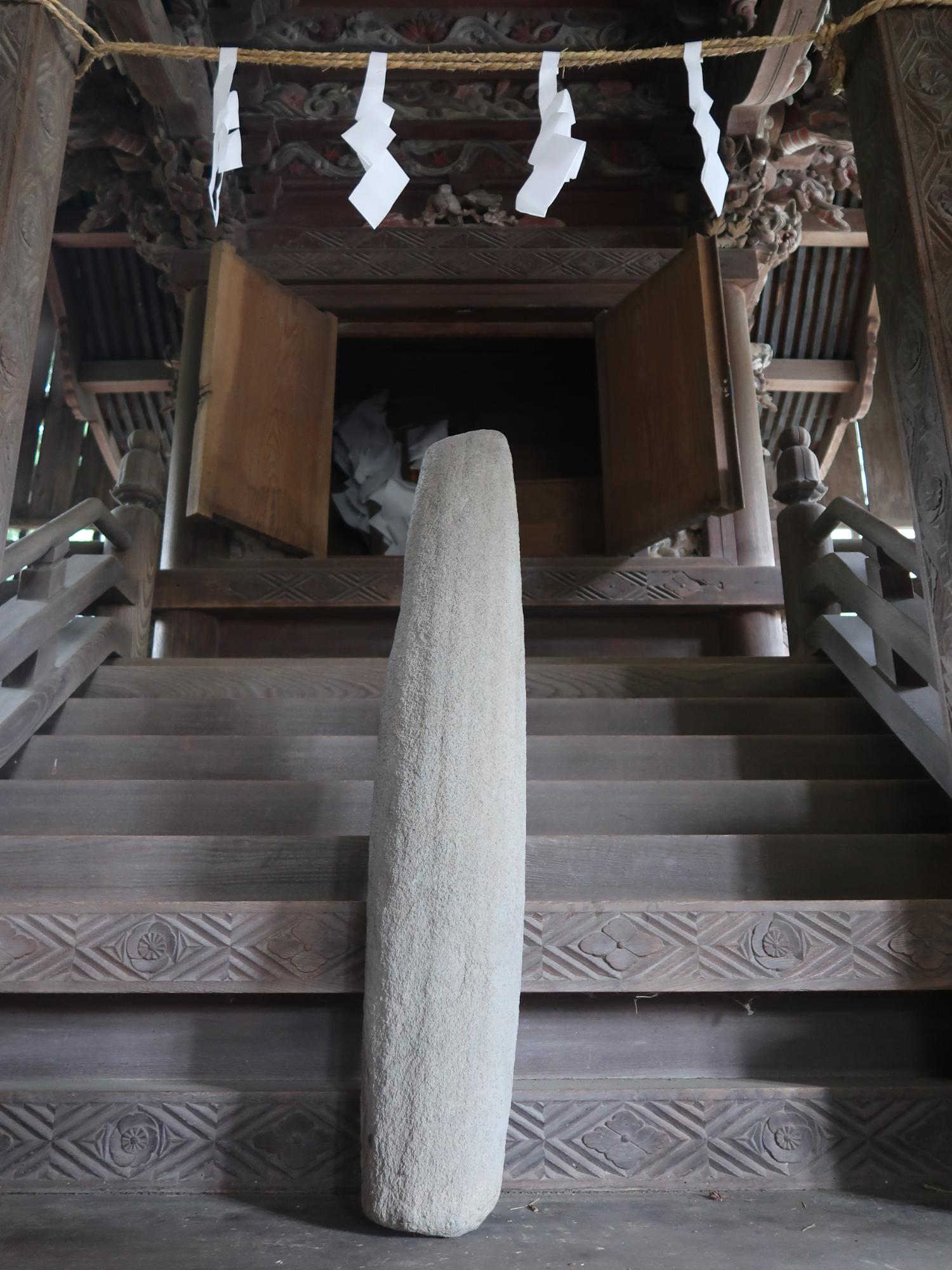 神社のお堂の前に置かれている灰色の石棒